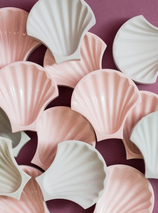 L'immagine mostra un gruppo di piccoli oggetti a forma di conchiglia, realizzati in ceramica e presentati in due tonalità pastello: rosa e bianco