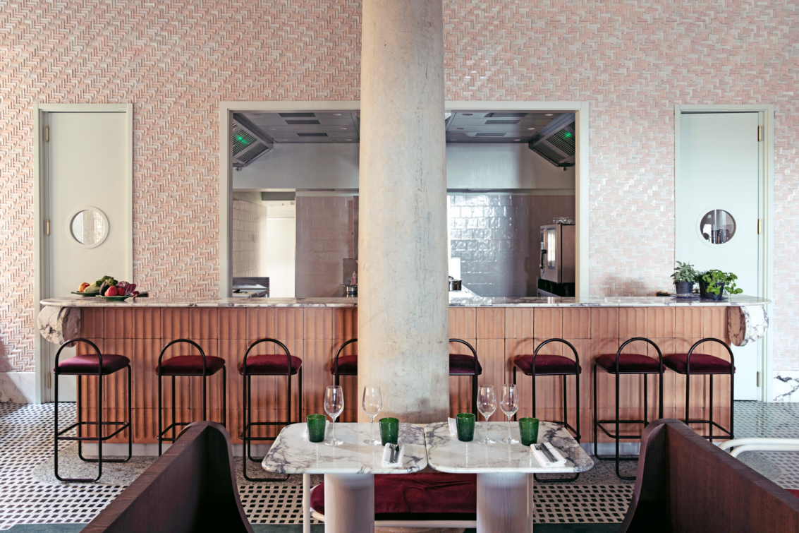 Interno di un ristorante moderno con bancone in legno e marmo.